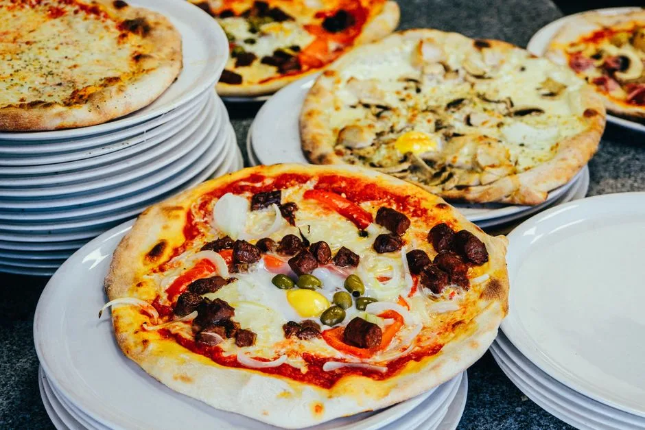 Deliciosa variedad de pizzas gourmet presentadas elegantemente en platos apilados, perfectas para amantes de la comida.