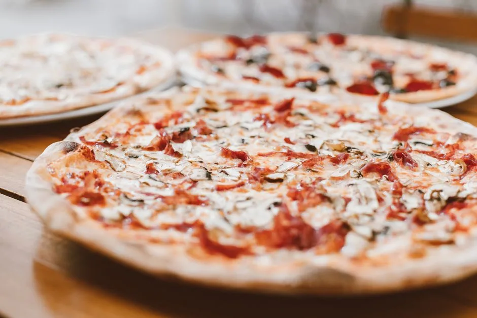 Primer plano de pizzas recién horneadas con champiñones servidas en una mesa de madera.