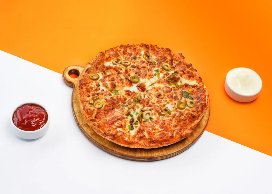 Una pizza sabrosa con aceitunas verdes, acompañada de salsas sobre un fondo vibrante.