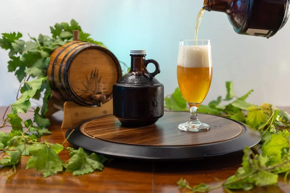 Cerveza artesanal vertida en un vaso con un barril de madera y hojas de parra en el fondo para lograr una apariencia rústica.