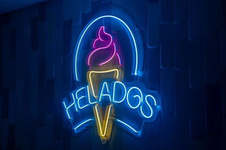 Un vibrante letrero de helado de neón ilumina una pared oscura, creando una atmósfera animada.