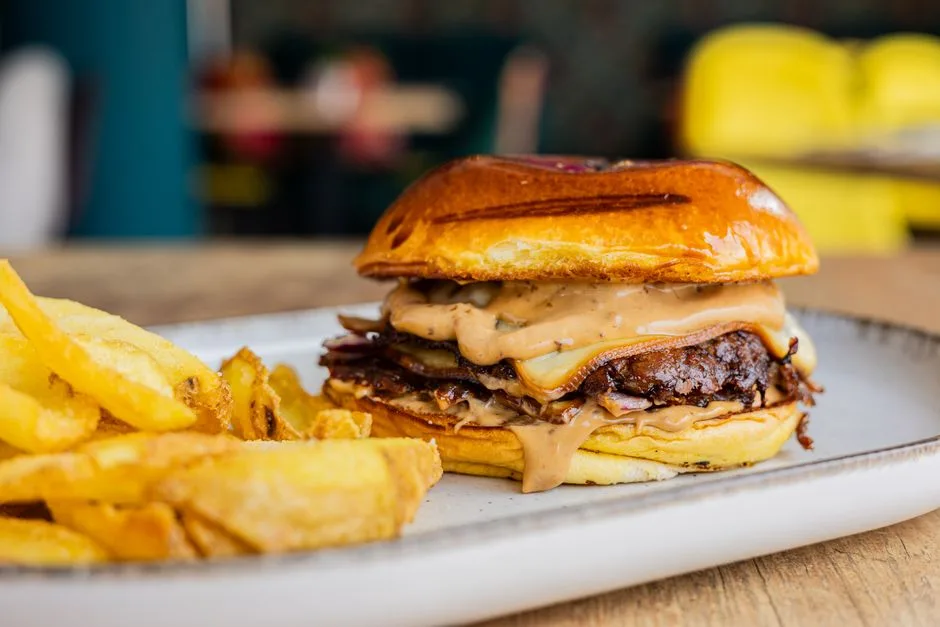 Hamburguesa gourmet que hace agua la boca y papas fritas crujientes servidas en un plato elegante.